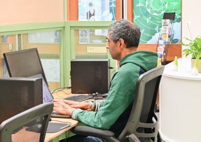 Man wearing green jumper at desk using a laptop in The Green Community Hub Worcester